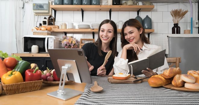 Female and female or LGBT couples are happily cooking bread together with happy smiling face in kitchen at home..