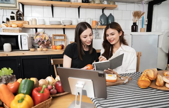 Female and female or LGBT couples are happily cooking bread together with happy smiling face in kitchen at home..