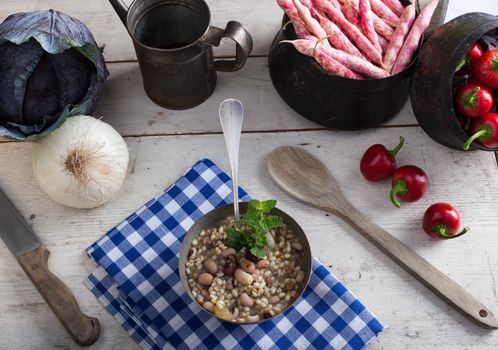 A bowl of minestrone soup and other vegetables on the table