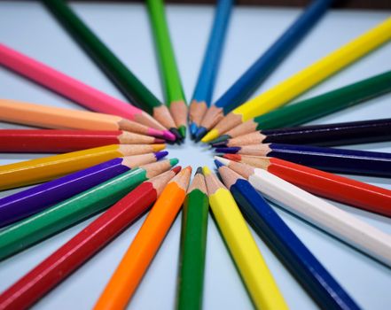 Closeup colorful pencil on blue paper background. Macro of a group pencils in a circle. Business concept, teamwork, united group