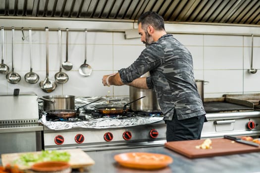 Professional cook is preparing meal in restaurant's kitchen.