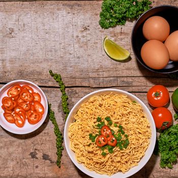 noodle in bowl and ingredients on wood background top view