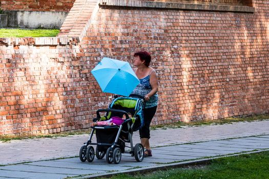 Woman walking with baby in stroller on alleys of park in Alba Iulia, Romania, 2021