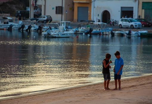 LAMPEDUSA, ITALY - AUGUST, 01: Two little boys play in the shoreline of Lampedusa at sunset on August 01, 2018