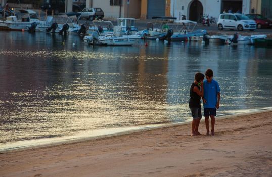 LAMPEDUSA, ITALY - AUGUST, 01: Two little boys play in the shoreline of Lampedusa at sunset on August 01, 2018