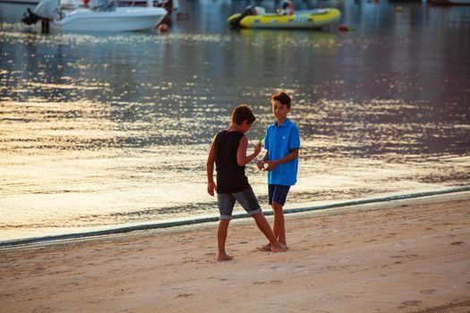 LAMPEDUSA, ITALY - AUGUST, 01: Two little boys play in the shoreline of Lampedusa at sunset on August 01, 2018