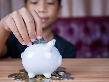 Boy saving money in a white pig piggy bank.Saving concept. Saving for the future.