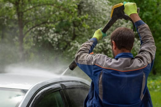 The car is washed at the car wash. Washing the car from dirt. High pressure water spraying equipment for washing car surfaces.