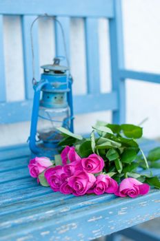 a bouquet of bright pink roses on a blue bench with a blue vintage lamp women's day on march 8, mother's day. High quality photo