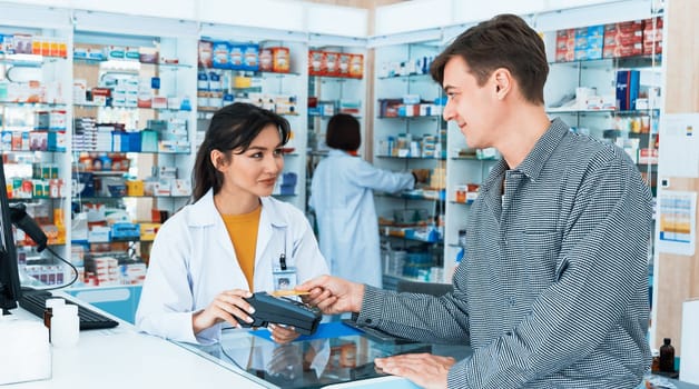 Payment by credit card with payment terminal in qualified drugstore. Modern financial payment of electric money. Caucasian customer purchase medication in pharmacy with prescription from pharmacist.