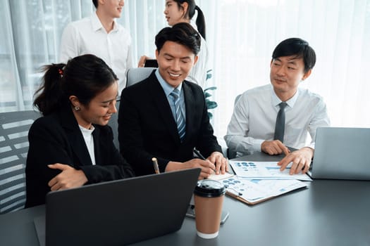 Harmony in office concept as business people analyzing dashboard paper together in workplace. Young colleagues give ideas at manager desk for discussion or strategy planning about project.