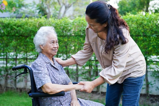 Caregiver help Asian elderly woman disability patient sitting on wheelchair in park, medical concept.