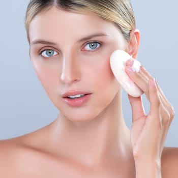 Closeup alluring beautiful female model applying powder puff for facial makeup concept. Portrait of flawless perfect cosmetic skin woman put powder foundation on her face in isolated background.