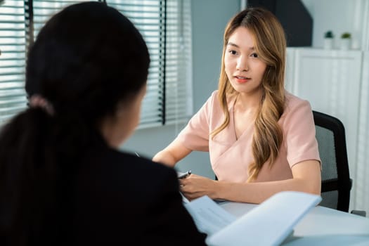 A young female asian candidate tries to impress her interviewer by being competent. International company, multicultural environment in workplace.