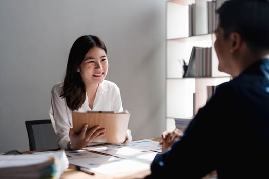 Two business people talk project strategy at office meeting room. Businessman discuss project planning with colleague at modern workplace while having conversation and advice on financial data report...