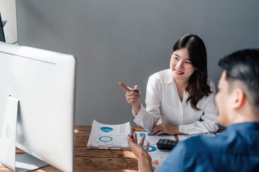 Two business people talk project strategy at office meeting room. Businessman discuss project planning with colleague at modern workplace while having conversation and advice on financial data report...