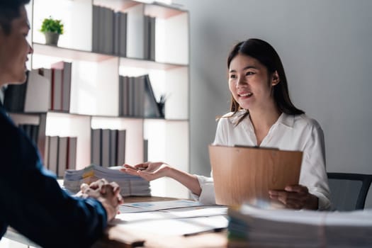 Two business people talk project strategy at office meeting room. Businessman discuss project planning with colleague at modern workplace while having conversation and advice on financial data report...