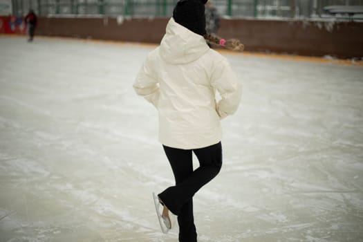 Girl on skates. Winter holidays. Ice skating. Sports details. Exercise on ice. Figure skating.