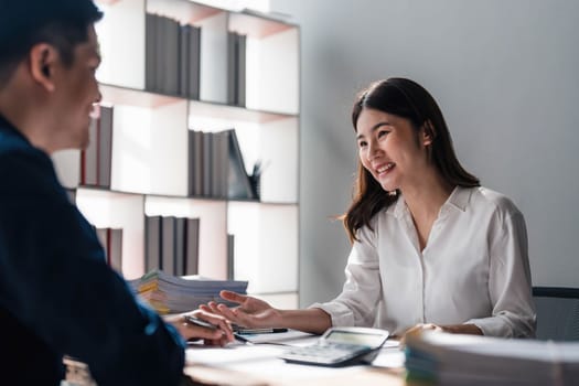 Two business people talk project strategy at office meeting room. Businessman discuss project planning with colleague at modern workplace while having conversation and advice on financial data report...