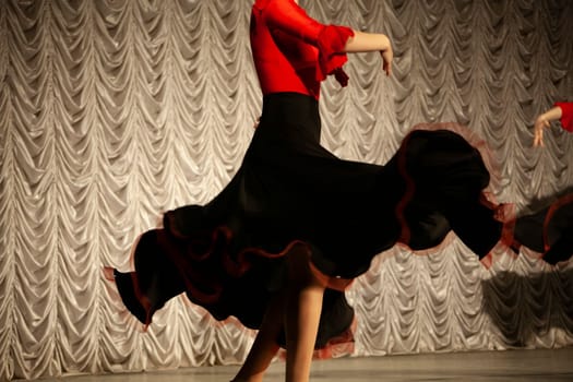 Spanish dance. Black dress. Dancer on stage. Details of speech. Incendiary movement. Beautiful girl spinning in long dress.