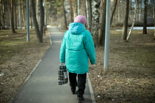 Woman in Russia walks down street. Pensioner in city. Girl from back. Simple urban environment and girl.