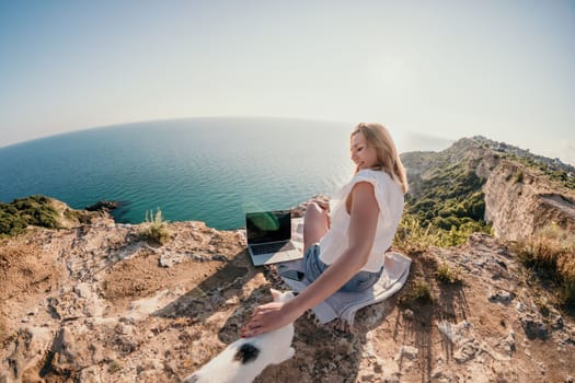 Woman sea laptop. Business woman in yellow hat working on laptop by sea. Close up on hands of pretty lady typing on computer outdoors summer day. Freelance, digital nomad, travel and holidays concept.