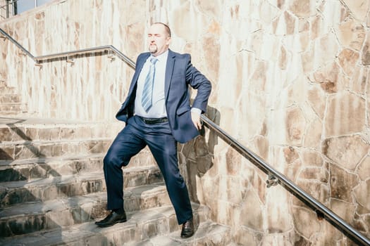Portrait of a senior professional man in a suit with various problems. A middle-aged businessman with a briefcase descends the stairs.