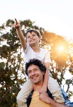 Dad, do you see that. a happy boy pointing at something while being carried by his father outdoors