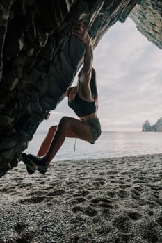 A girl climbs a rock. The athlete trains in nature. Woman overcomes difficult climbing route. Extreme hobby. Tourist woman rock climber hiking on mountains rocks over beautiful sea coast