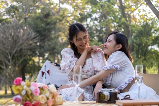 Two beautiful Asian female besties cuddle, sharing a special moment together, and enjoy a picnic feeling friendly.