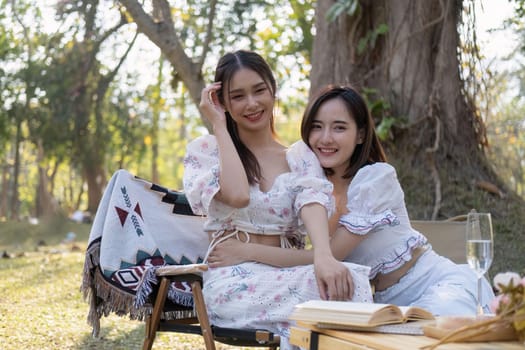 Two beautiful Asian female besties cuddle, sharing a special moment together, and enjoy a picnic feeling friendly.