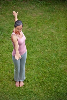 Focussing on her posture. High angle shot of an attractive mature woman doing yoga outdoors