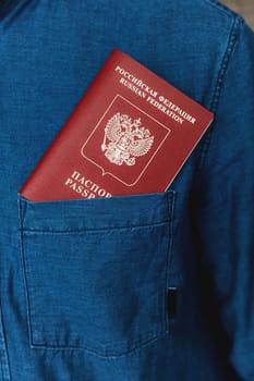 Passport in the pocket of a denim shirt close-up. Man without a face, breast pocket with identity document.