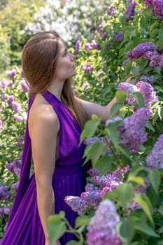 portrait of young woman with long hair outdoors in blooming lilac garden.