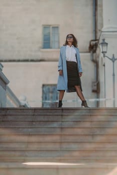 Woman walks in the city, lifestyle. Young beautiful woman in a loose light sweater, brown skirt and sneakers with a hat