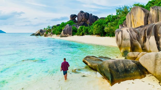 Young men at a white tropical beach Anse Source d'Argent beach La Digue Seychelles Islands.