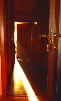 A beam of light falling on the floor through the open door in room