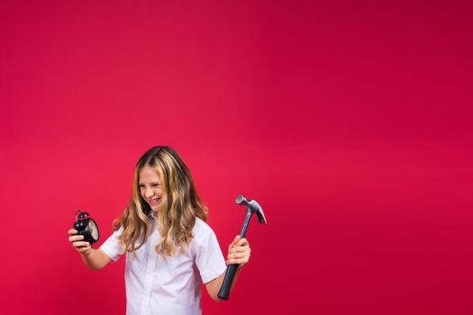 Kid girl holding hammer and alarm clock smiling with happy and cool smile on face. showing teeth.