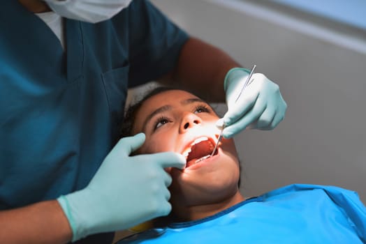 You will be smiling brightly in no time. a young little girl lying down on a dentist chair while getting a checkup from the dentist