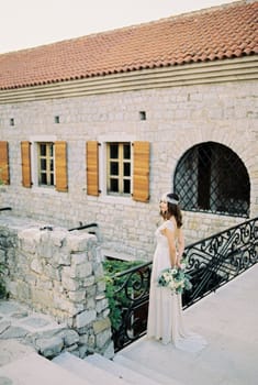 Bride with a bouquet stands on a bridge near a stone fortress. High quality photo