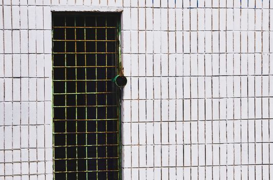 a hinged, sliding, or revolving barrier at the entrance to a building, room, or vehicle, or in the framework of a cupboard. Dark metal door hole with bars on a white tiled wall