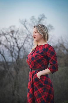 Attractive blonde girl in a red dress in the evening forest.