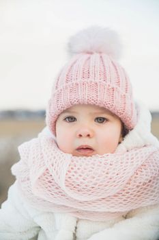 Adorable baby in a white fur coat.