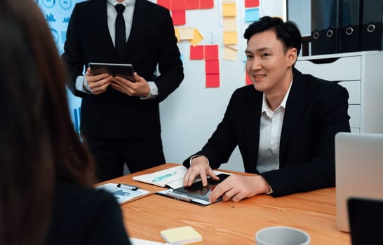 Confidence and asian businessman give presentation on financial analyzed by business intelligence in dashboard report to other people in board room meeting to promote harmony in workplace.