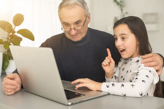 Grandfather and granddaughter spend time together use laptop, browse website, younger generation teach explain to older how to use modern tech concept.