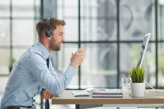 Young handsome male customer support phone operator with headset working in his office