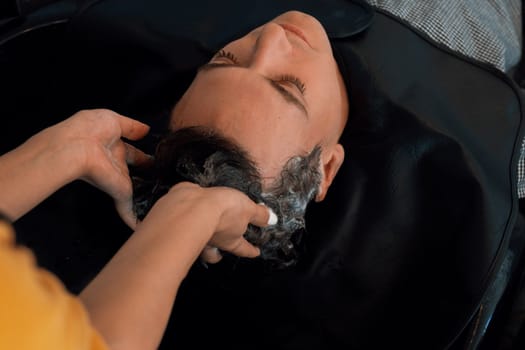 Closeup caucasian man getting hair wash by professional hairdresser with shampoo feels relax and comfortable . Qualified hairdresser with her barbershop, salon providing haircare concept.