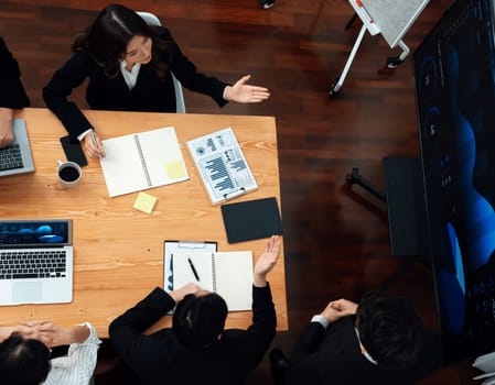 Top view manager or office worker give presentation in harmony conference room to business colleague, BI data dashboard on screen and pile of financial analyzed data reports on meeting table.