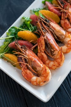 Grilled tiger prawns or shrimps with orange grapefruit and greens on a plate