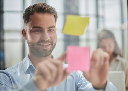 businessman is working on a project. Business man pointing at a note on the glass wall